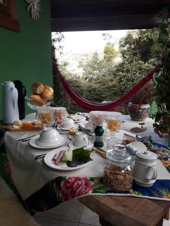 Mesa do café da manhã posta na varanda, com rede vermelha ao fundo
